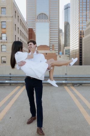 A romantic moment captured between a couple on a rooftop with downtown skyscrapers in the background.