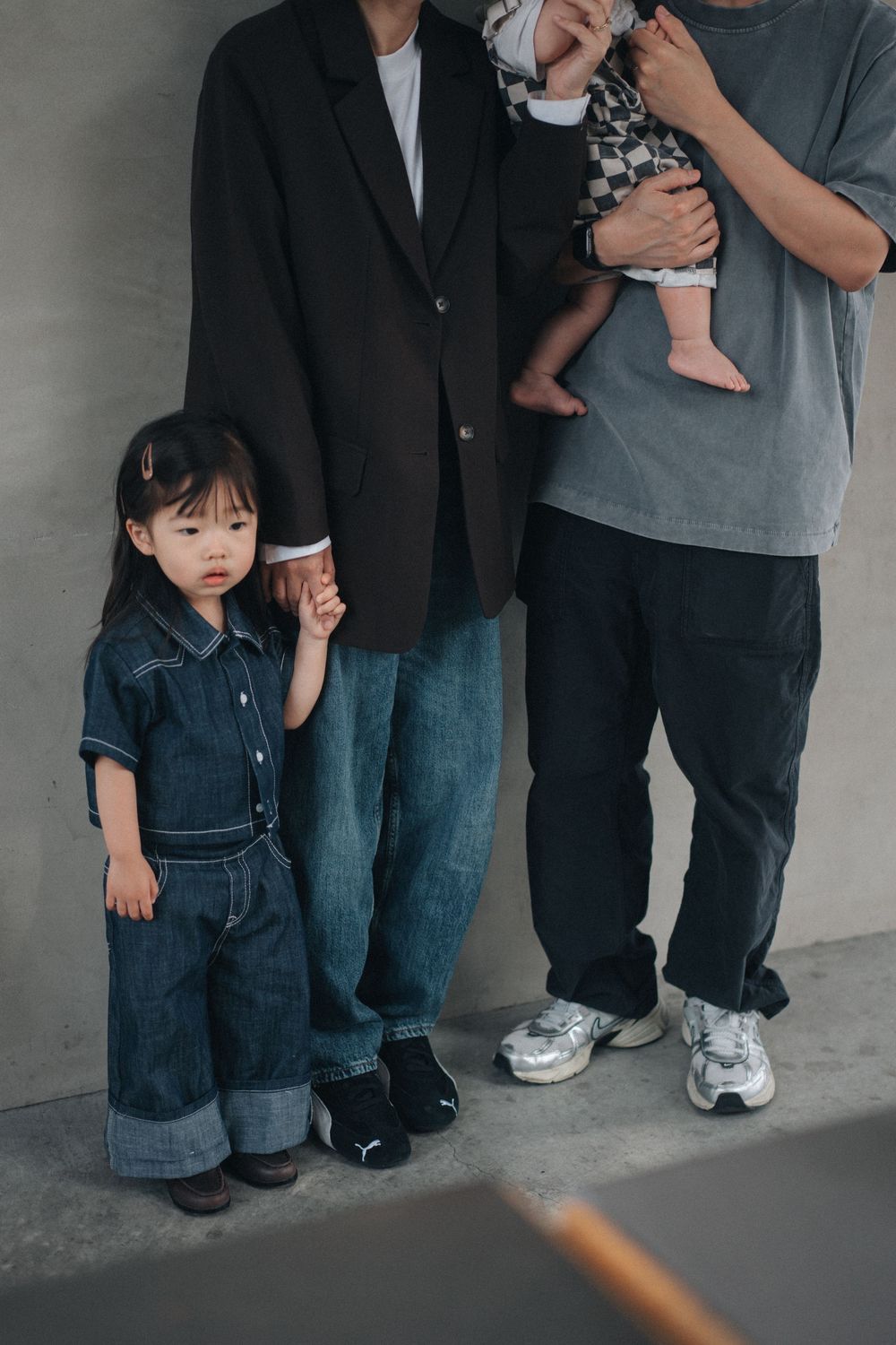 A series of cropped photos showing legs and feet of adults and children standing together against a gray wall.
