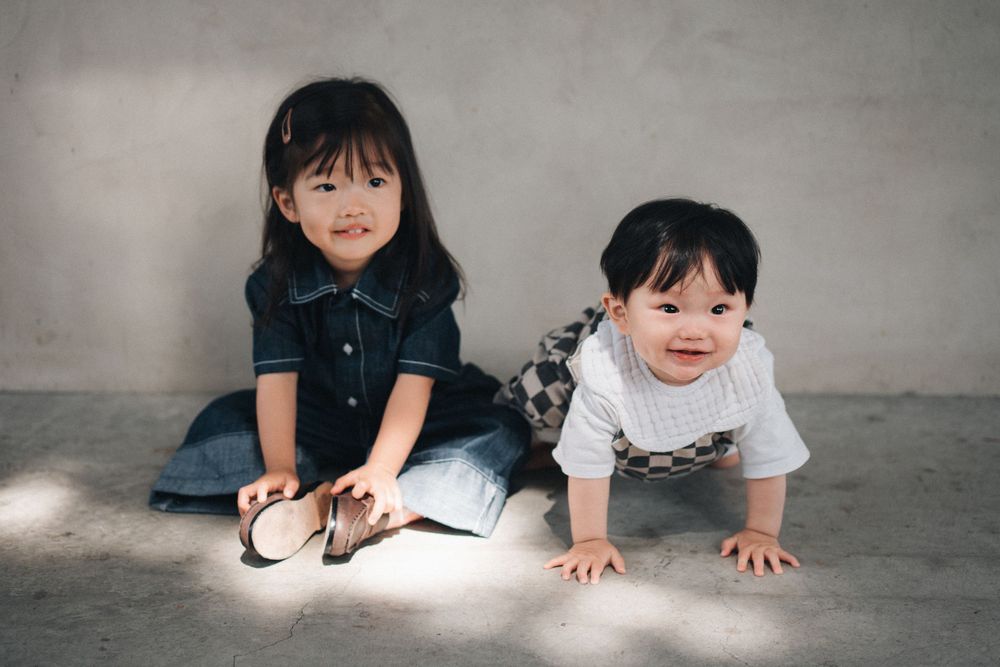 Six sequential photos show a crawling baby progressing across a gray studio floor in a casual outfit.