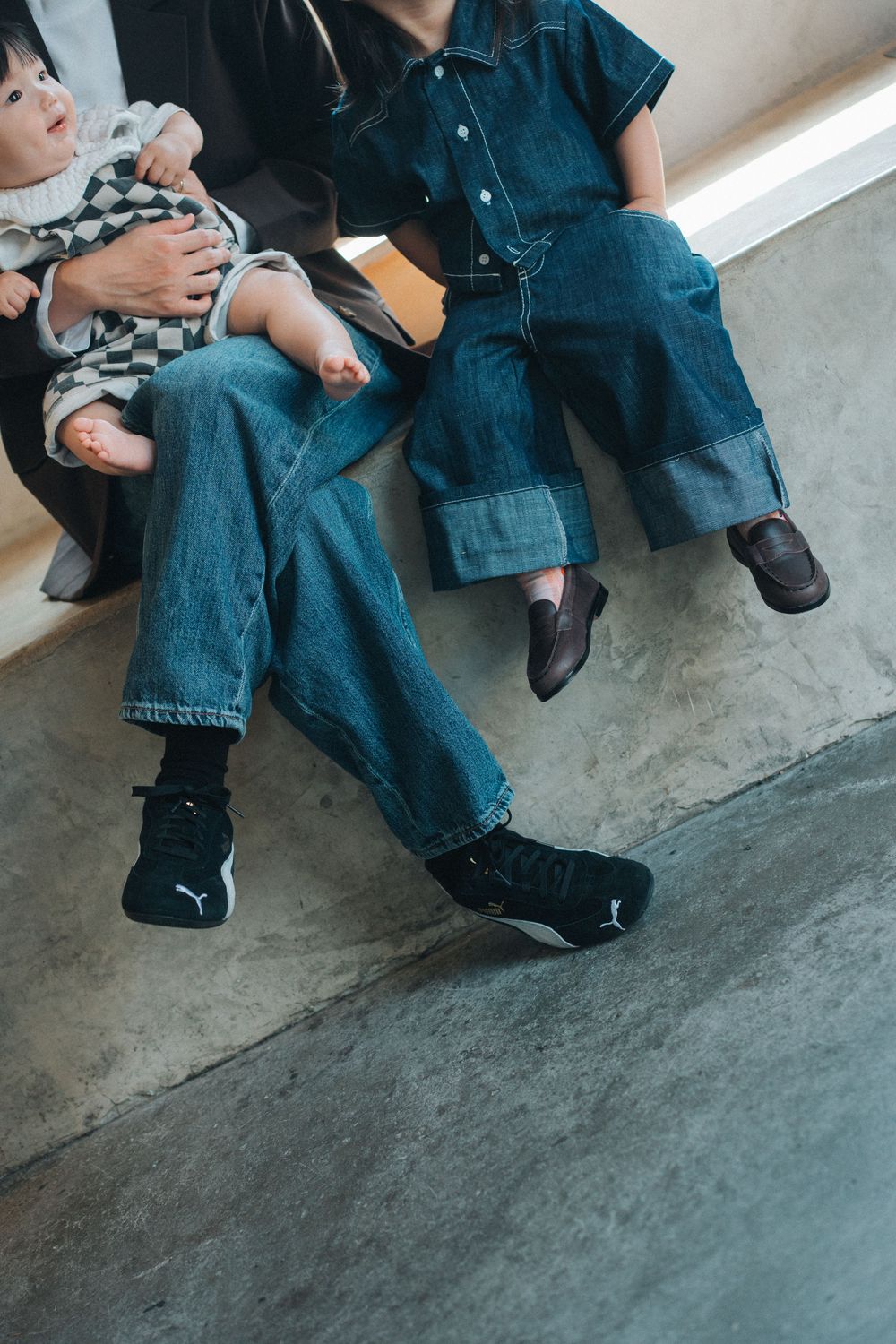 Matching denim outfits with black footwear shown in a cropped photo sitting on concrete floor.