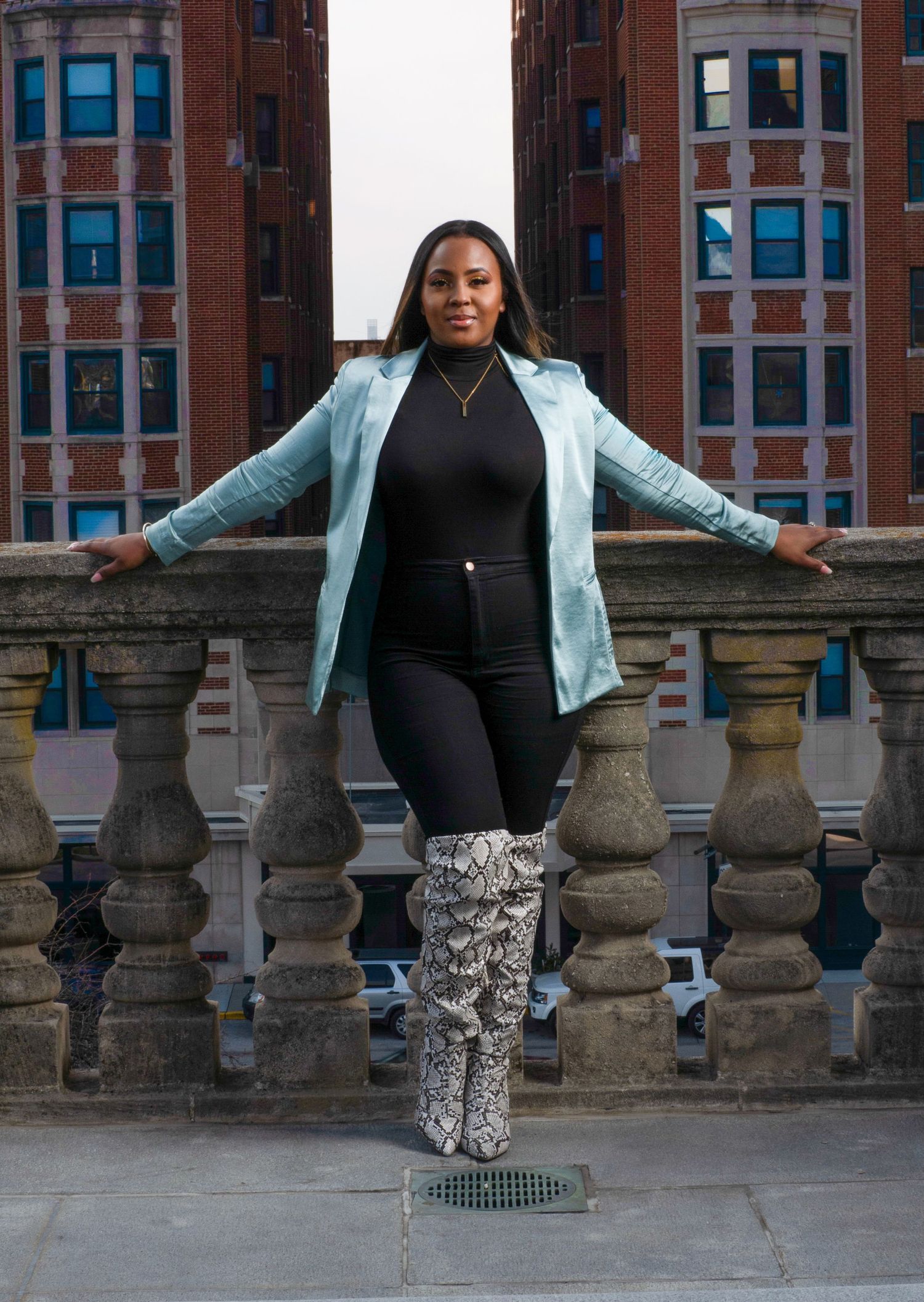 A light blue blazer and snakeskin boots create a stunning contrast against stone balustrades of a historic building.