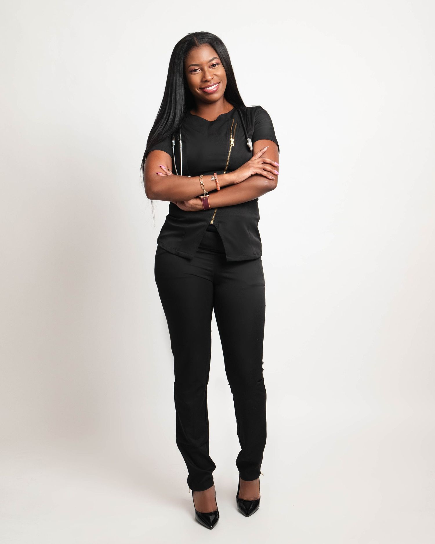Professional looking business person wearing black attire stands confidently with arms crossed against white background.