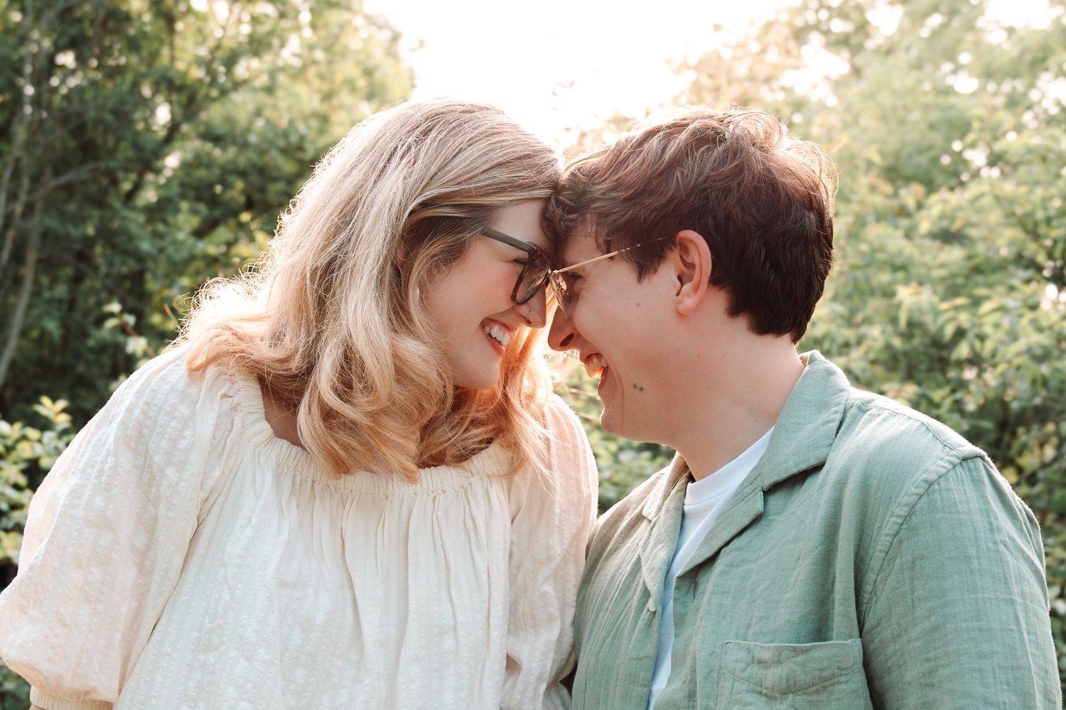 Romantic couple sharing intimate moment while touching foreheads in outdoor garden setting.