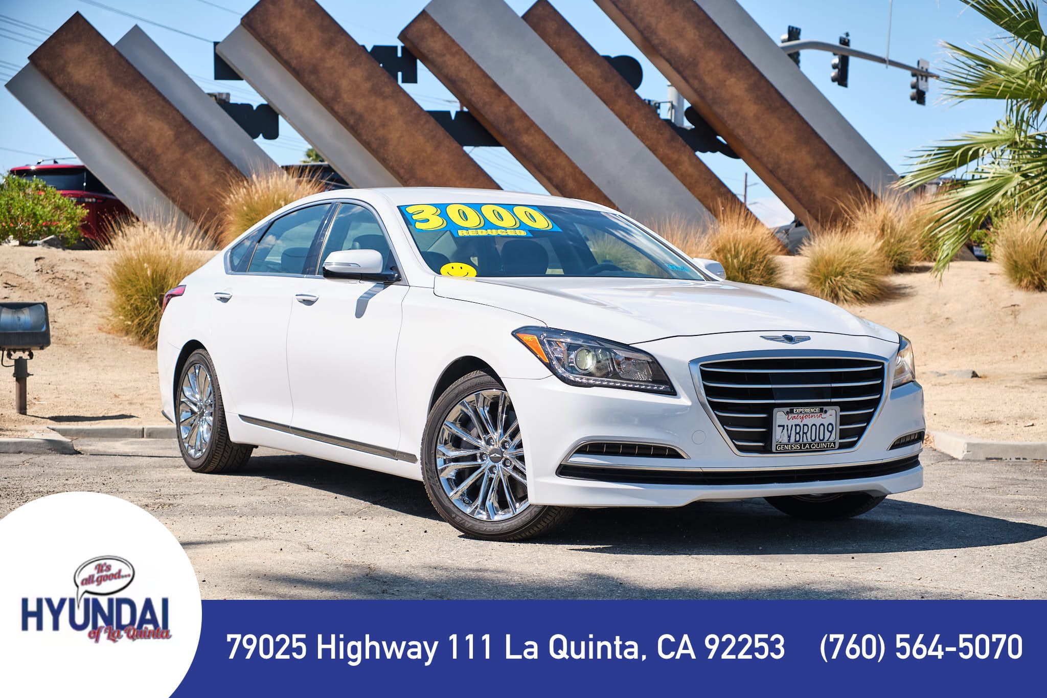 White Hyundai Genesis luxury sedan showcased at dealership in front of modern architectural structure in La Quinta, California.