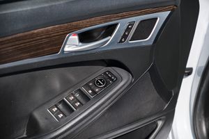 Door control panel of a luxury car featuring wood trim, window controls, and door lock buttons in a black interior.