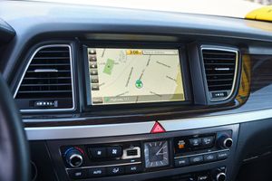 Modern car dashboard displaying GPS navigation system interface with map and turn directions on center console screen.