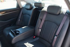 Black leather rear seats of a luxury car interior with center armrest and cup holders.