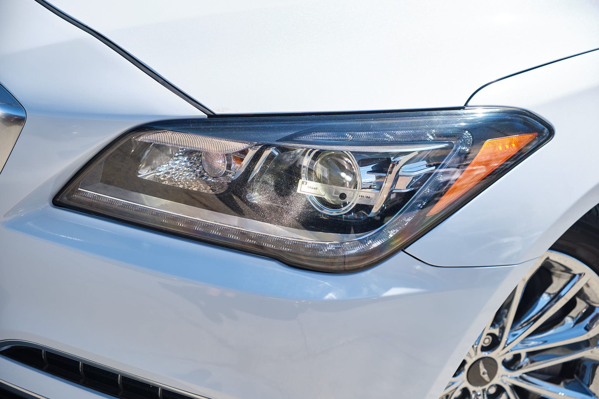 Close-up view of a modern LED headlight on a white luxury vehicle showing detailed lighting elements.