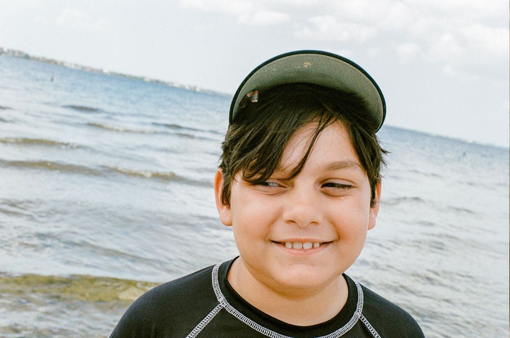 A young beachgoer wearing a black visor at the ocean.