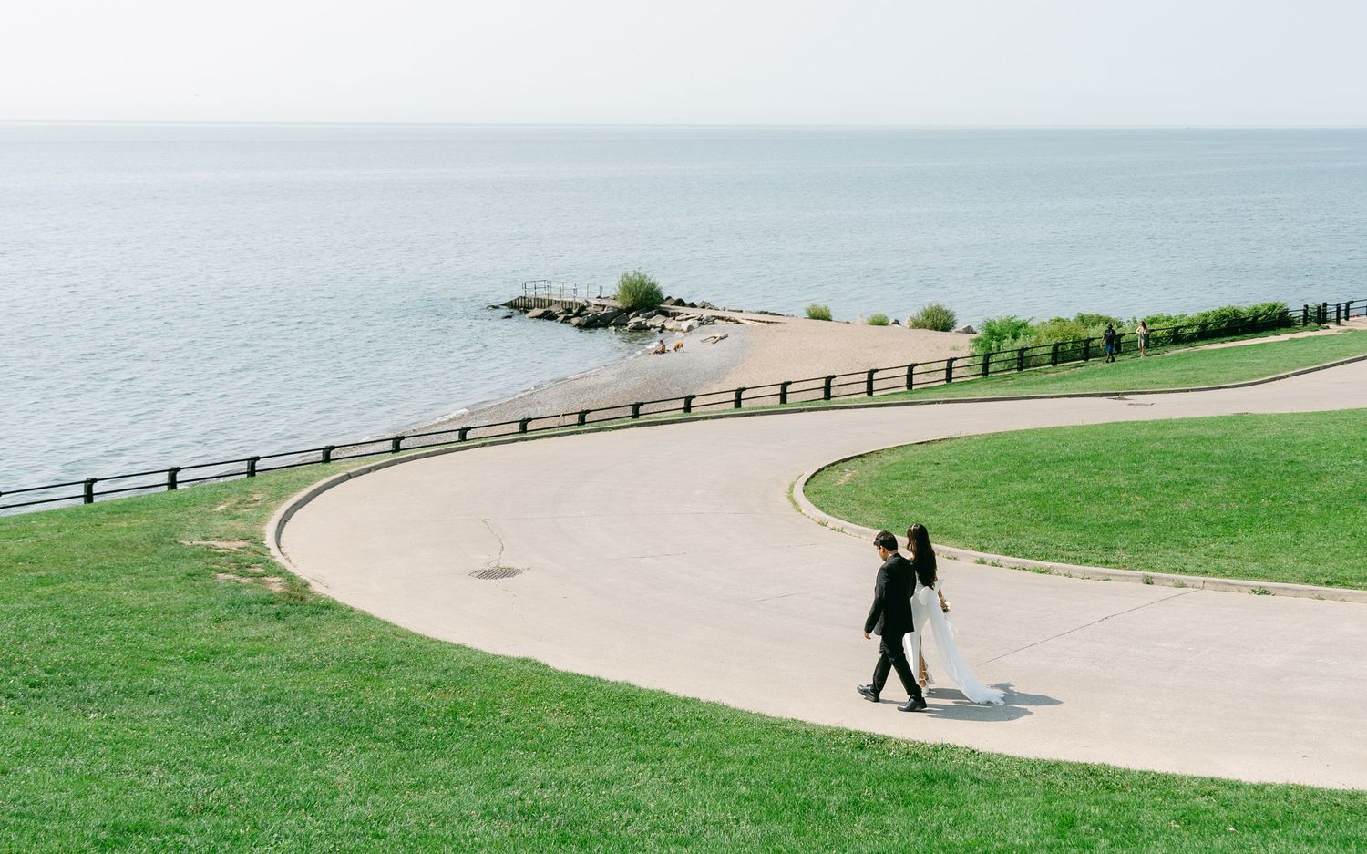 A solitary figure walks along a curved coastal pathway with ocean views.