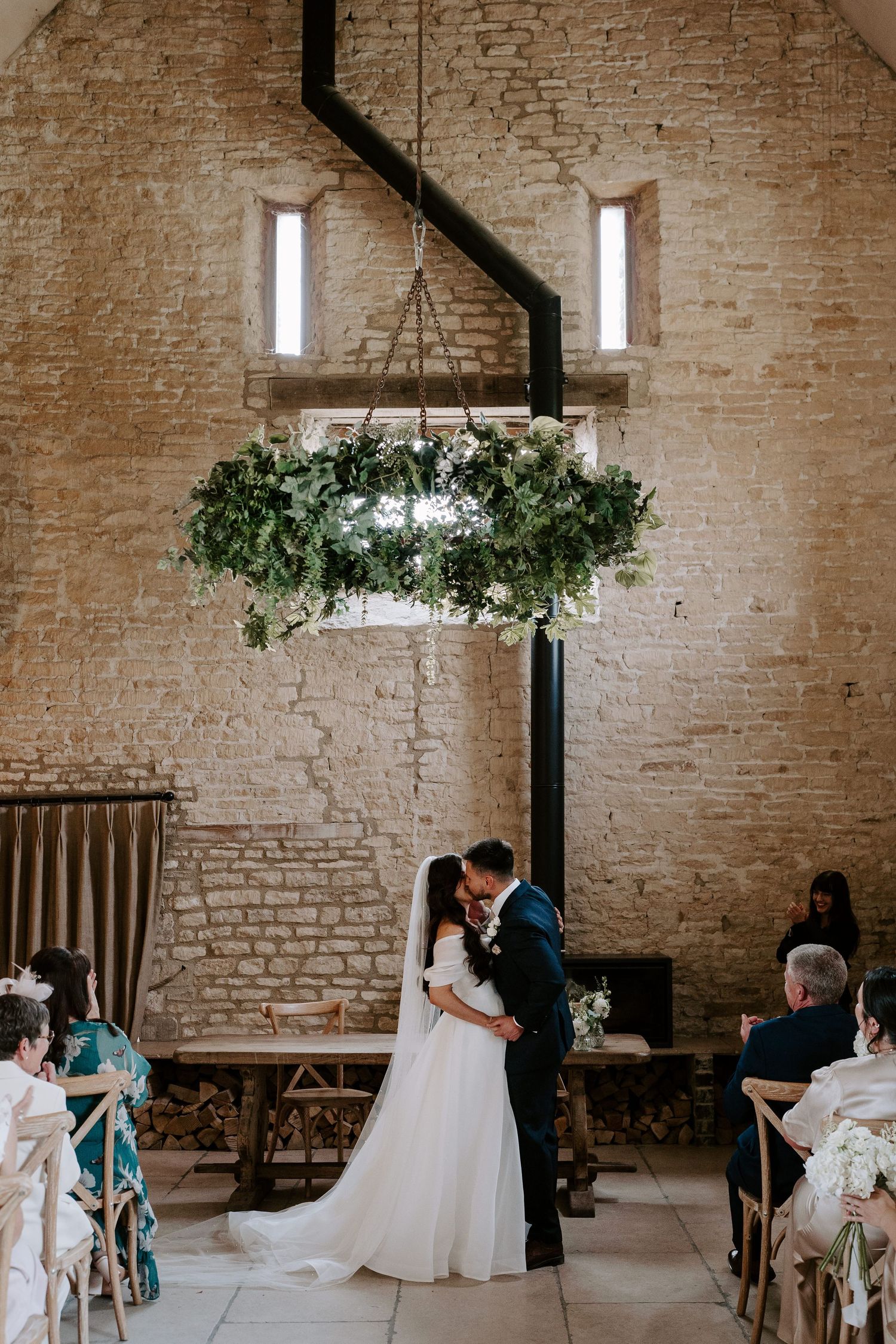 bride and groom sharing first kiss during wedding ceremony at yardspace old gore in cirencester