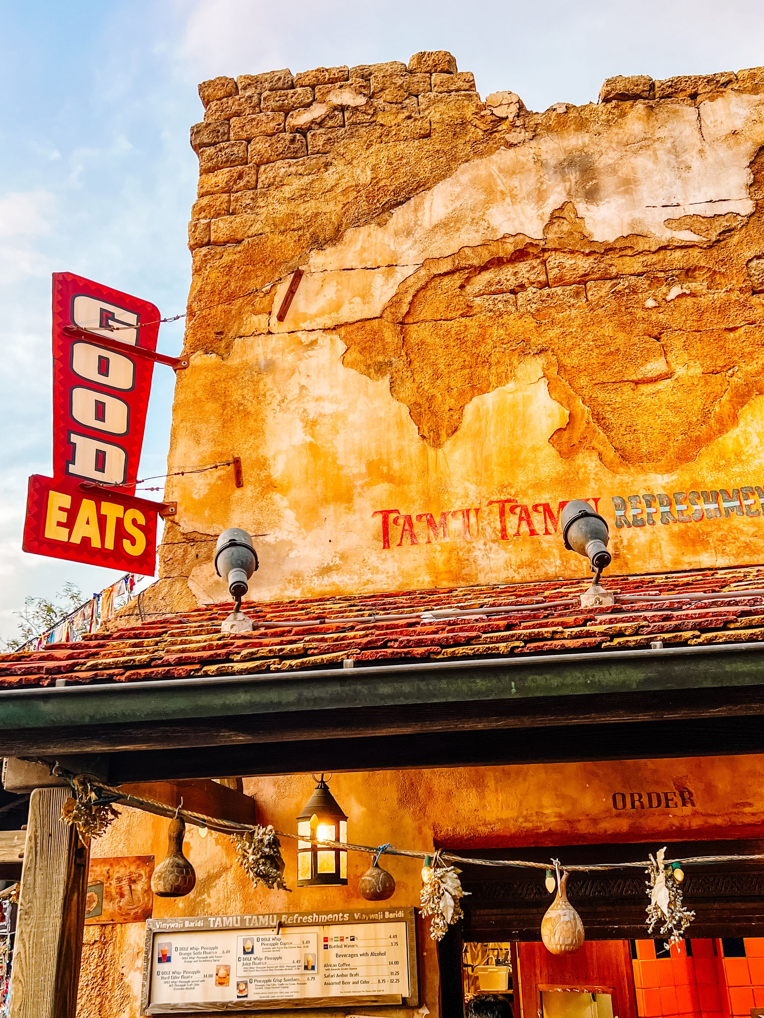 Rustic stone walls and wooden beam architecture of an old restaurant with vintage signage illuminated at dusk.