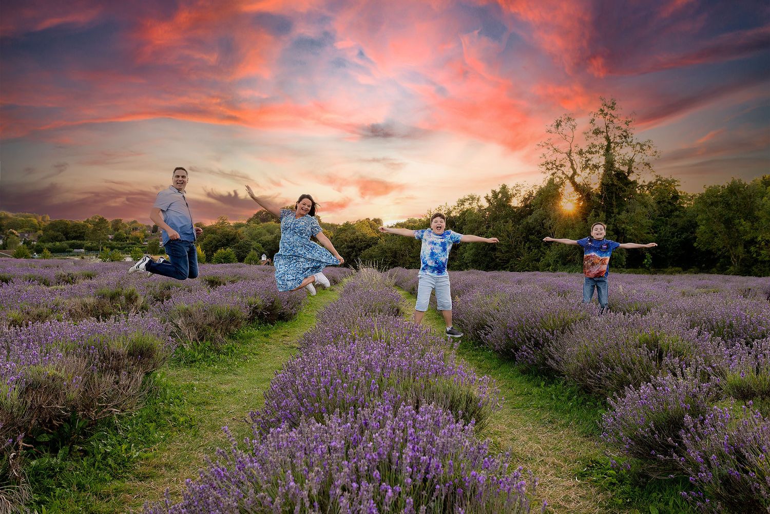 People jumping joyfully in a lavender field at sunset with vibrant pink and orange sky overhead.