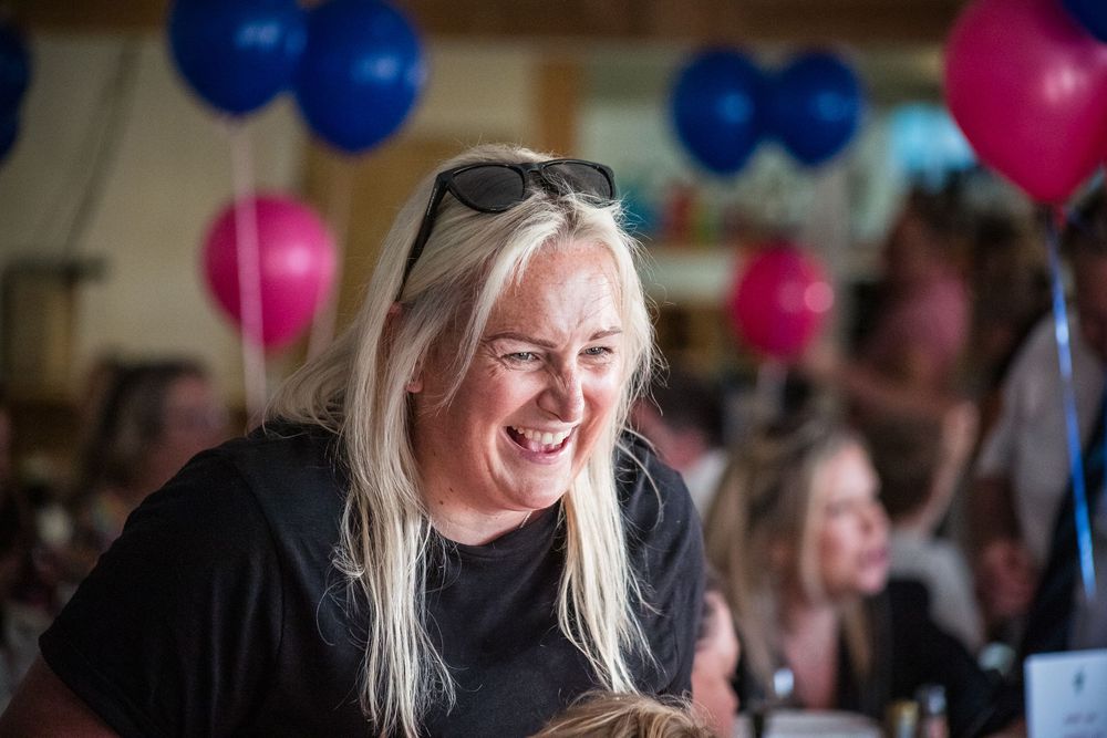 Woman with blonde hair laughing with balloons in the background at a sports awards night