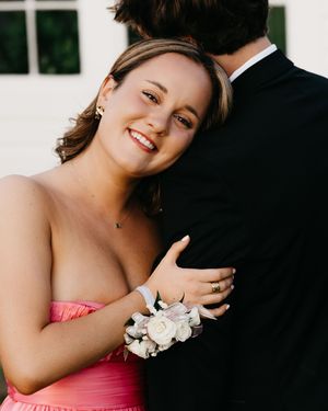 A prom photo showing a couple with corsage against a white wall.