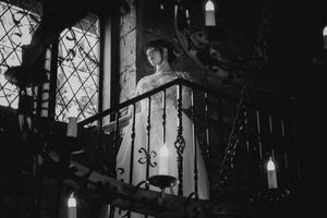 Black and white image of a cathedral interior with gothic arches and hanging pendant lights creating a dramatic atmosphere.