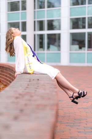 A sequence of photos shows someone in a white dress and heels sitting on a brick ledge in various relaxed poses.