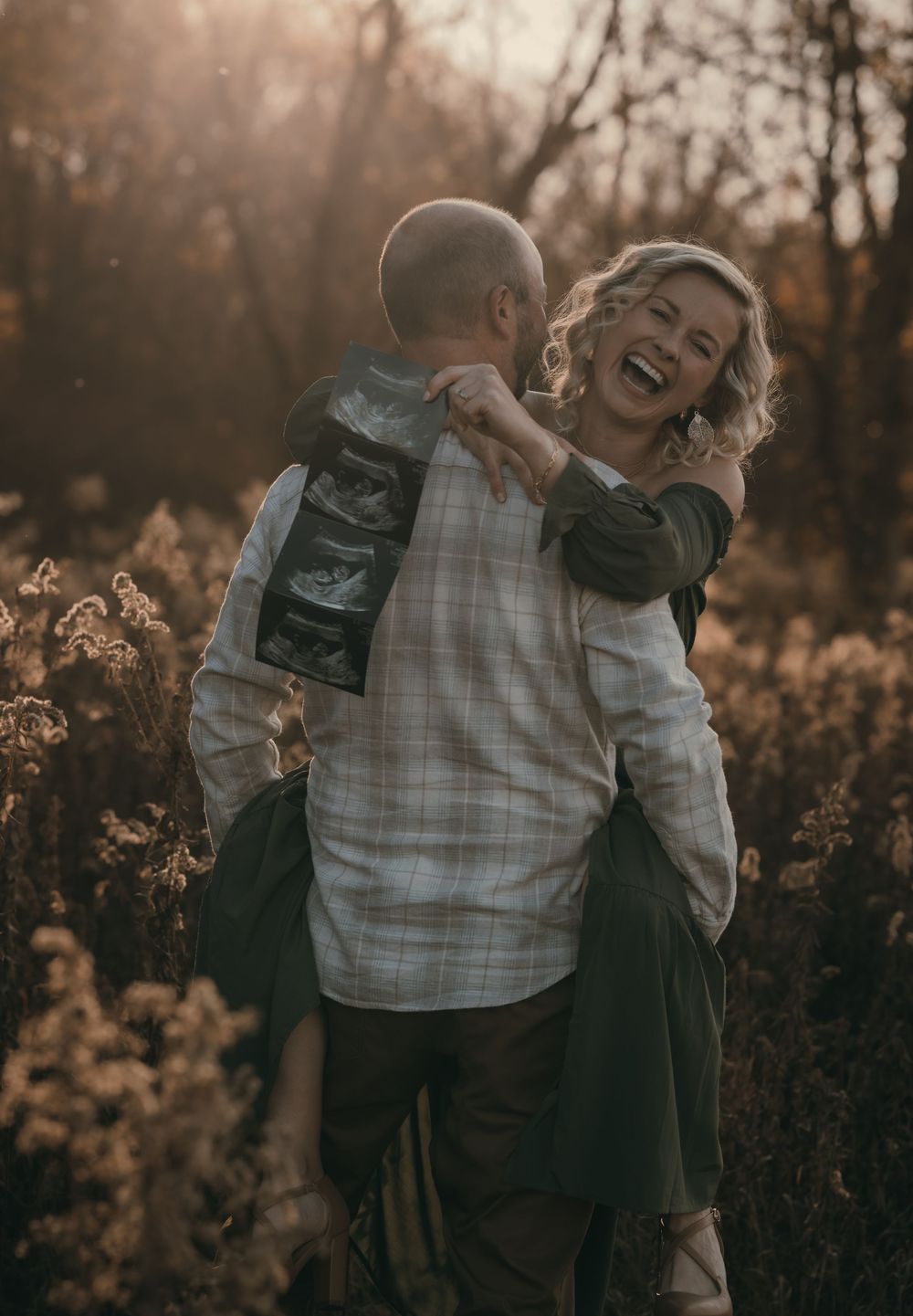 An intimate moment between a couple lit by golden sunset light in a field of tall grass.