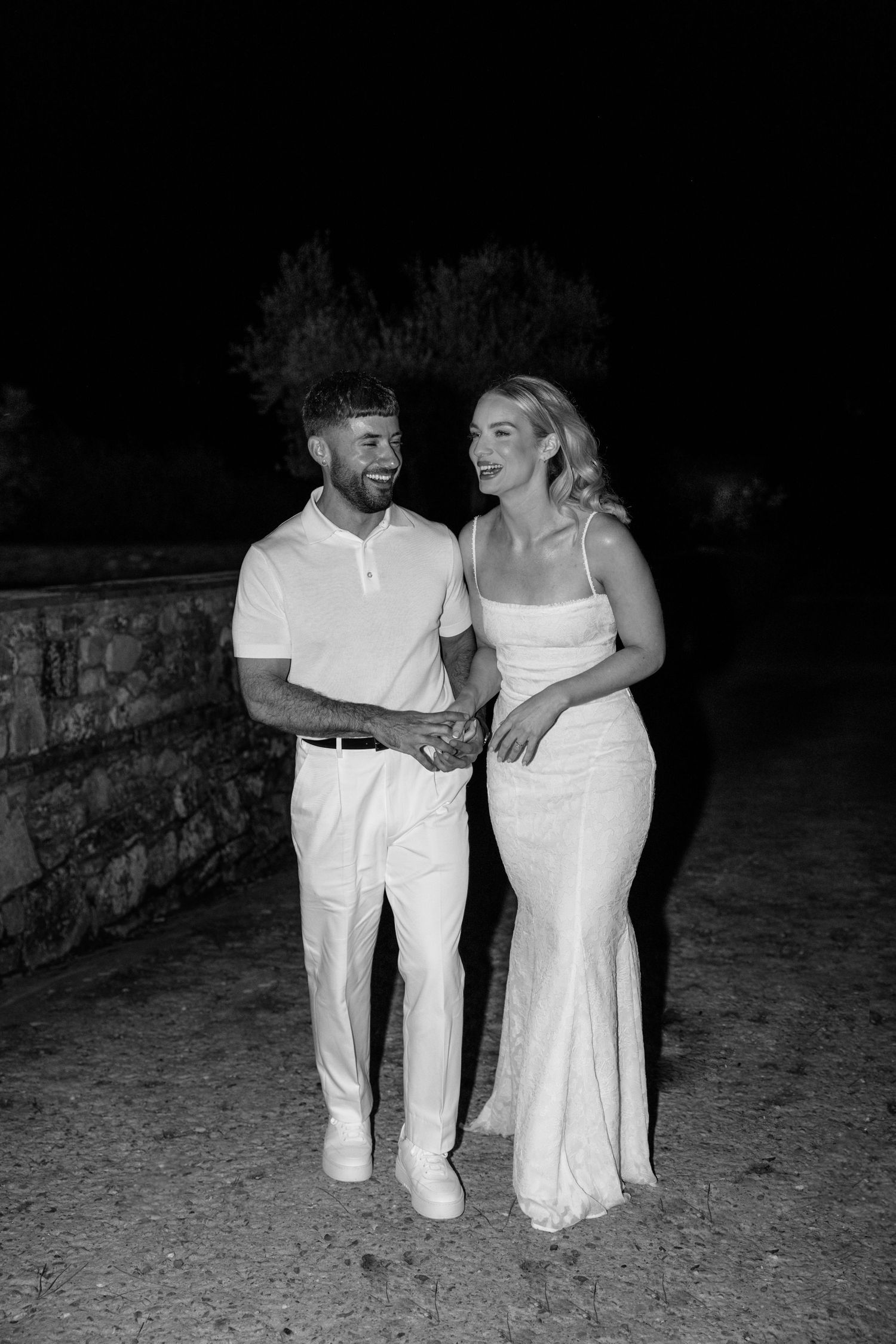 A black and white nighttime portrait of a couple in coordinating white outfits.