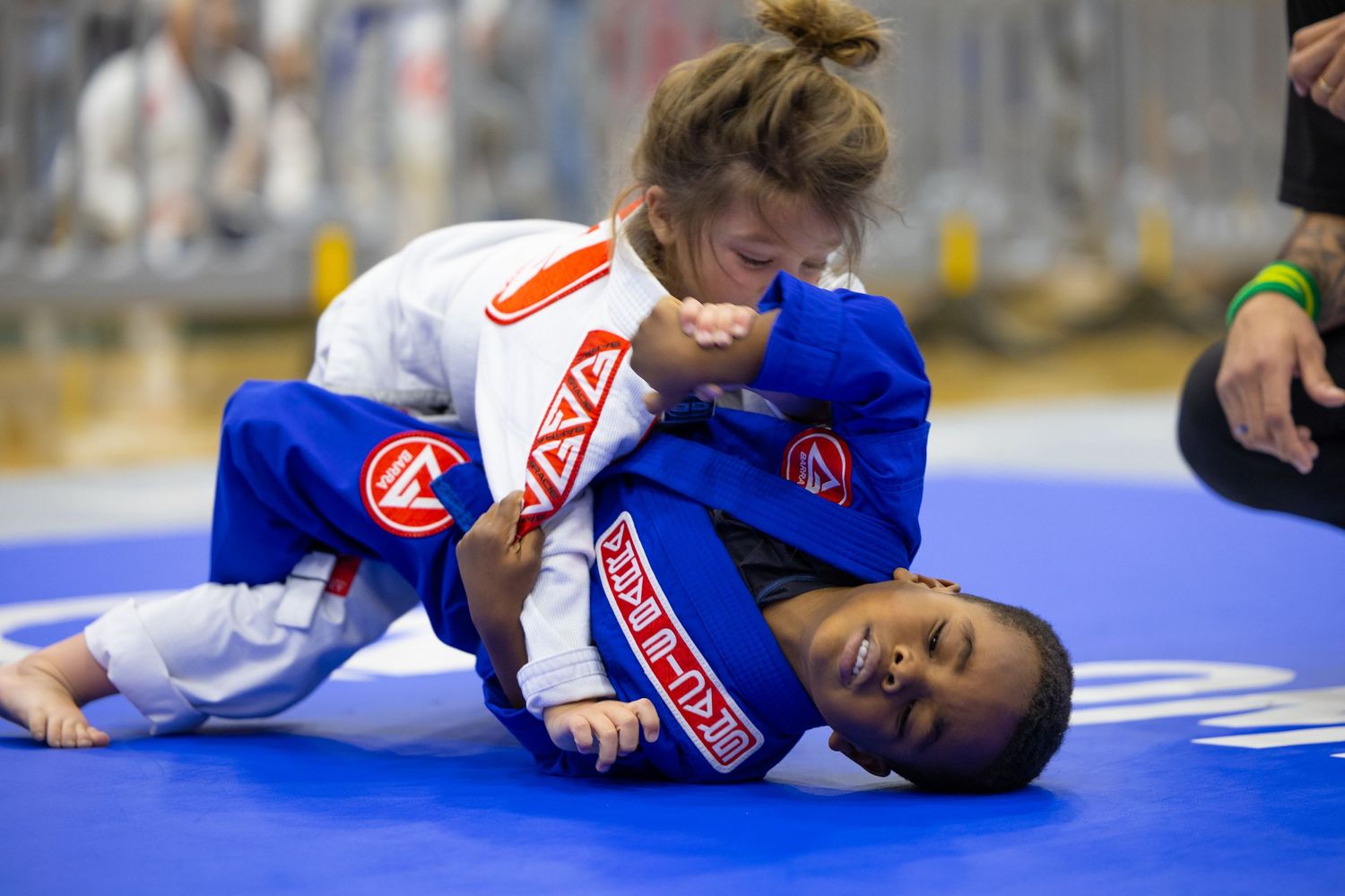 Athletes engage in ground grappling techniques during a jiu-jitsu tournament match.