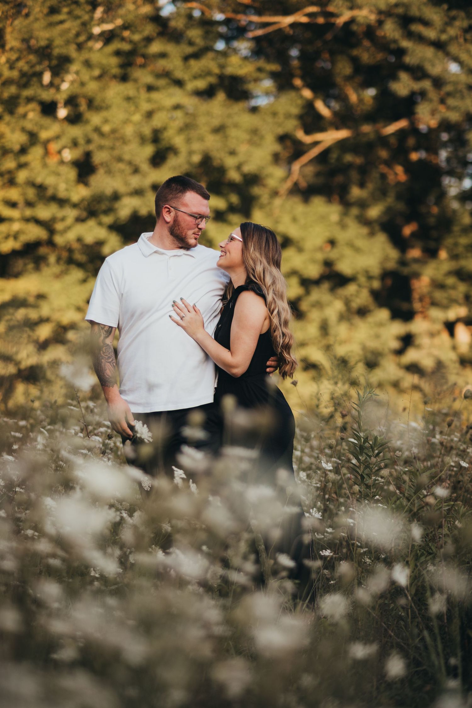 A romantic couple embraces in a scenic outdoor setting with golden sunlight filtering through autumn trees.