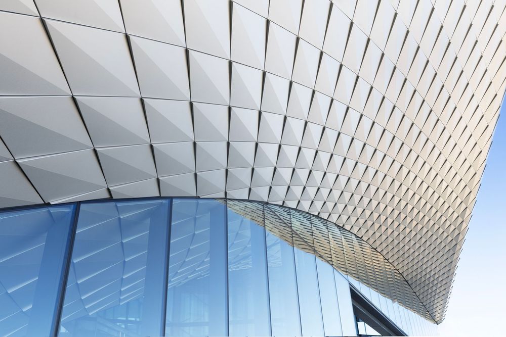 Olympic and Paralympic Museum modern architectural design featuring textured white panels curving against blue sky.