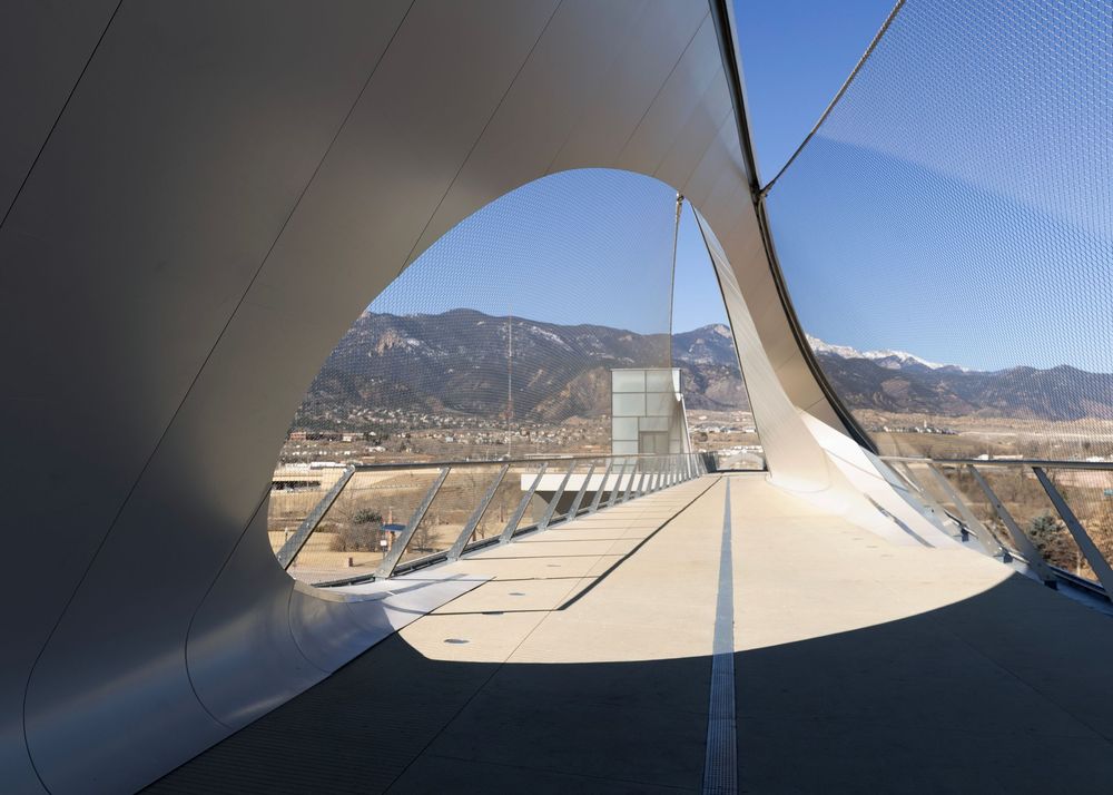 Olympic and Paralympic Museum bridge walkway with sculptural white curves offering panoramic mountain views.