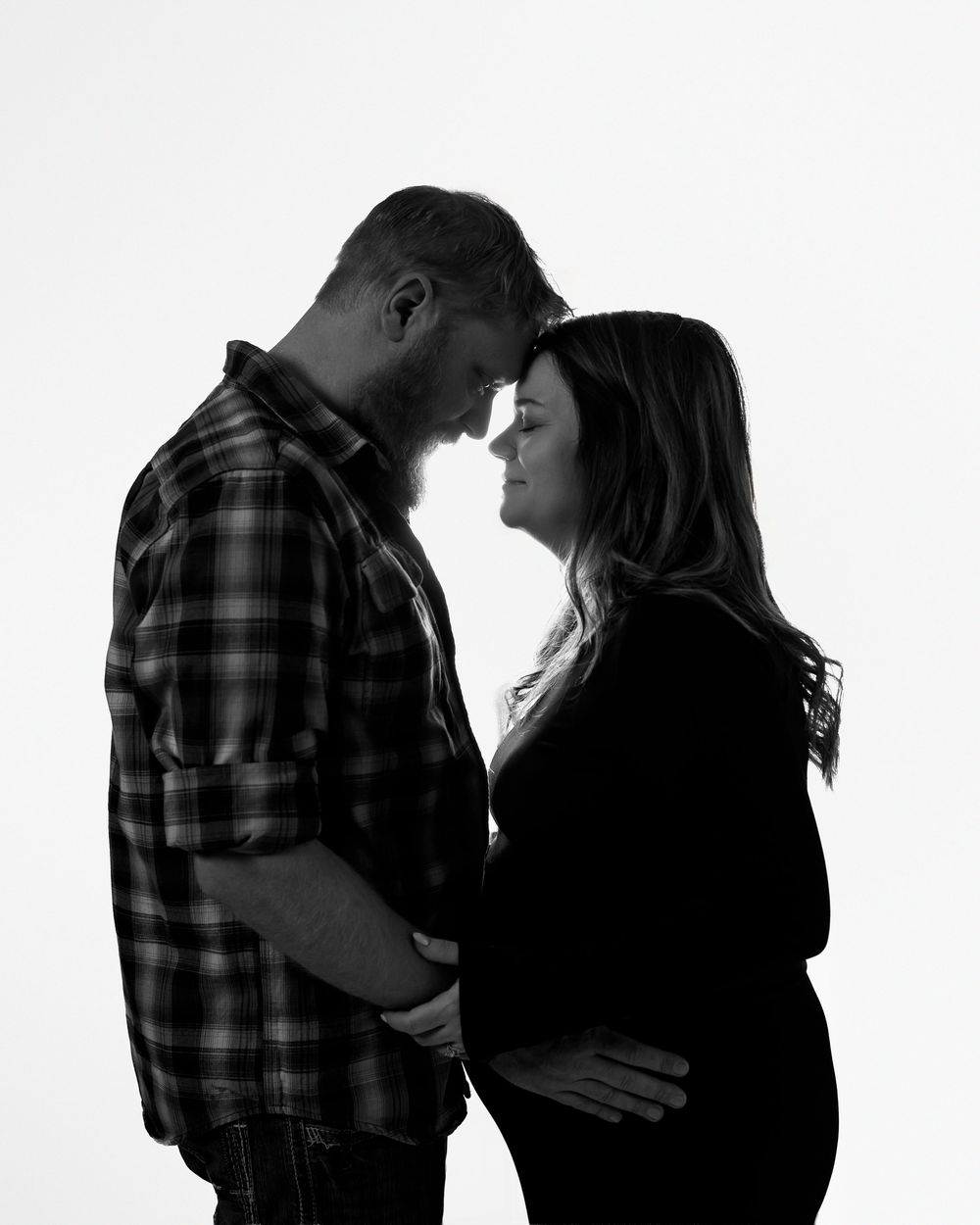 Black and white silhouette of an intimate couple in a tender moment, with the woman wearing a dark sweater and man in plaid.