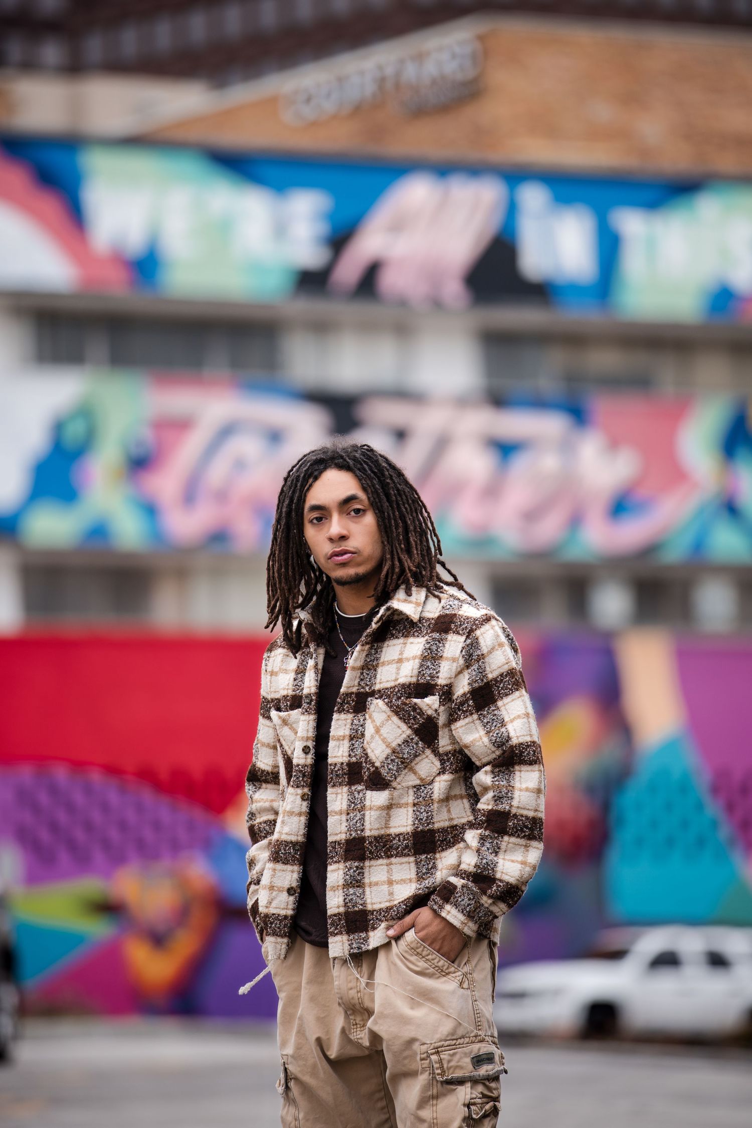 Street fashion photography with colorful graffiti wall backdrop and plaid jacket outfit.