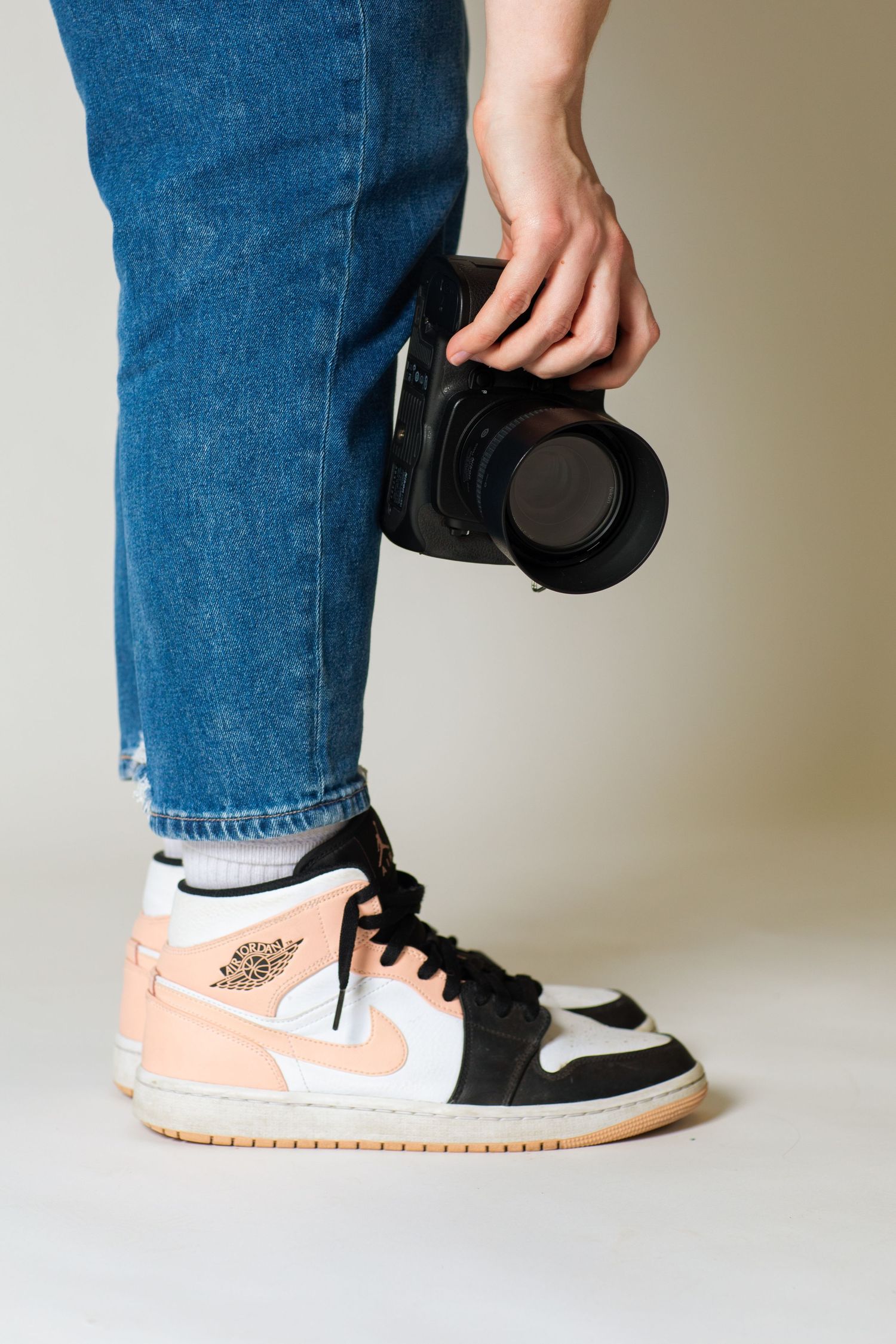 A photographer wearing Jordans and blue jeans holding a camera