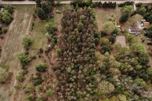 Aerial view of a rural property with trees and cleared land showing mixed forest and agricultural areas.