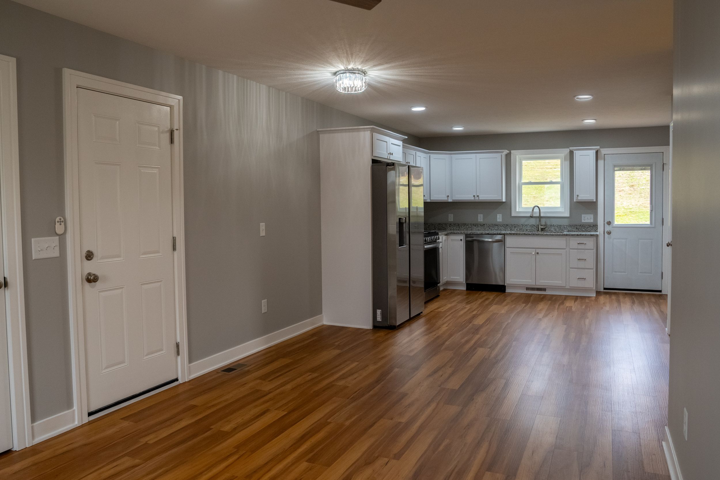Open concept kitchen and living area with stainless appliances, hardwood floors and recessed lighting.