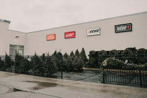 Retail storefront exterior with black fence and industrial signs mounted on gray wall in desaturated style.