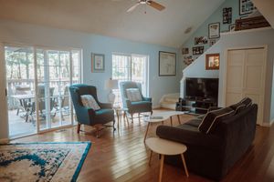 Cozy living room with hardwood floors, blue walls, French doors, and modern furniture arranged around a TV entertainment center.