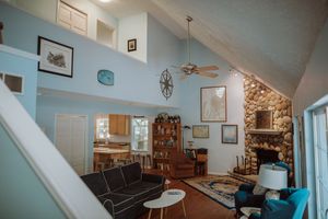 A cozy living room with vaulted ceilings features blue walls, stone fireplace, and mid-century modern furniture.