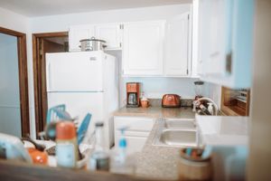 Modern white kitchen interior with granite countertops, coffee maker, and appliances in pastel blue and orange accents.