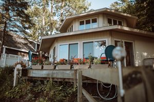 Modern two-story home with large windows and deck railing decorated with orange pumpkins during autumn.