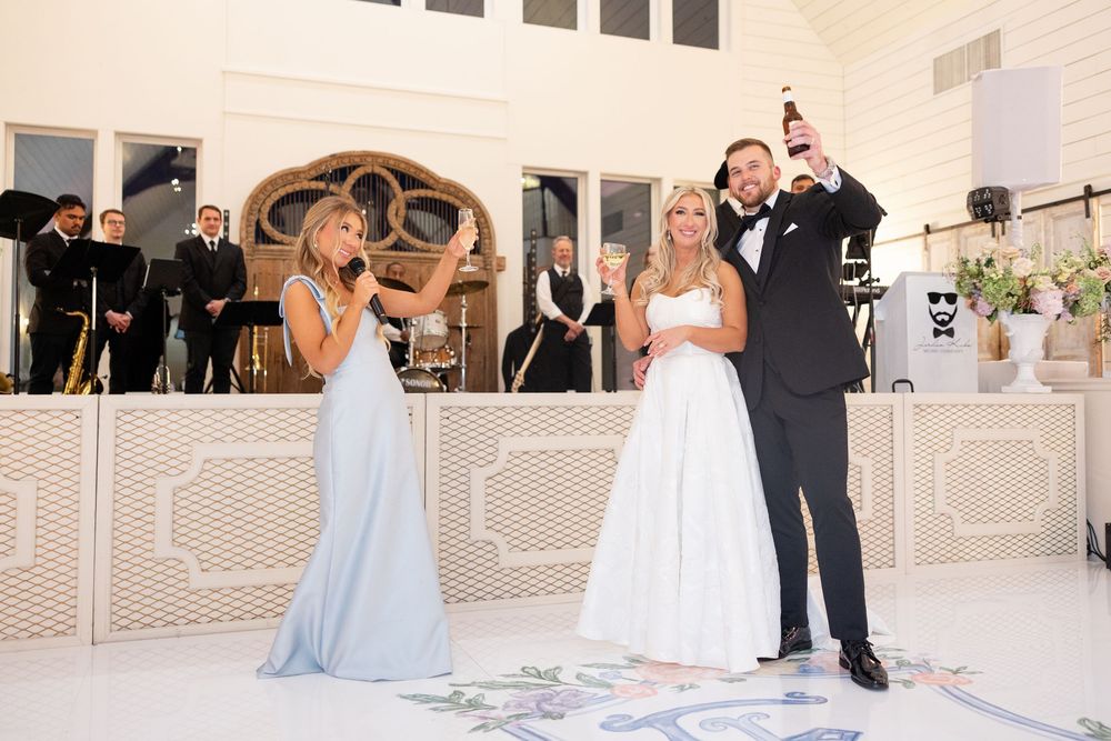 Bride and groom celebrate joyfully with champagne bottle raised during wedding reception toast with bridesmaid.