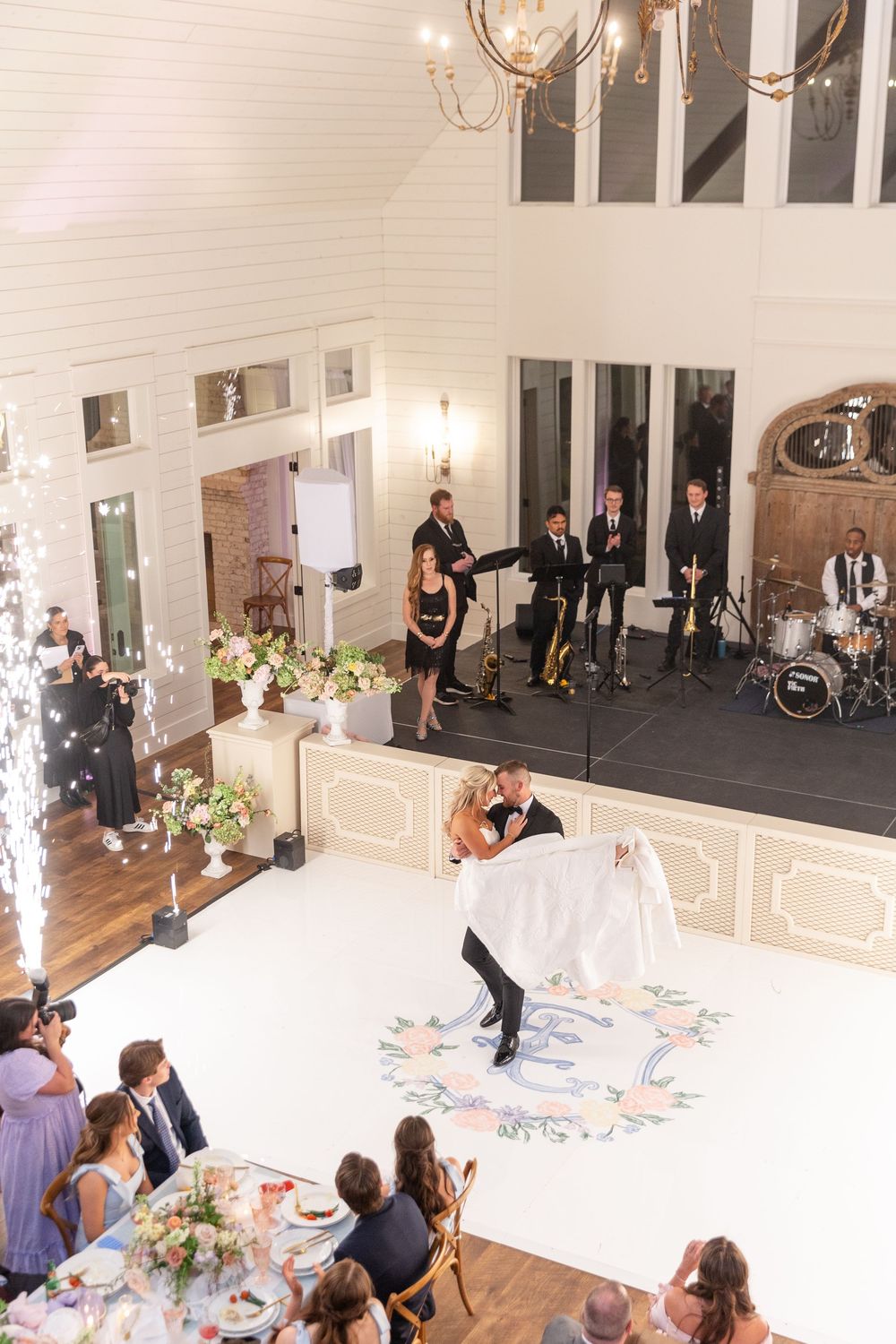 Aerial view of bride and groom first dance with cold sparkler fountains and live band at reception.