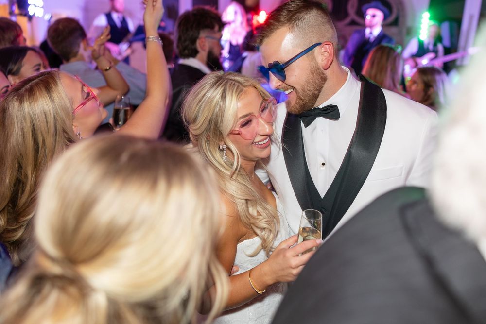 Bride and groom share an intimate moment on the wedding reception dance floor, groom in white tuxedo.