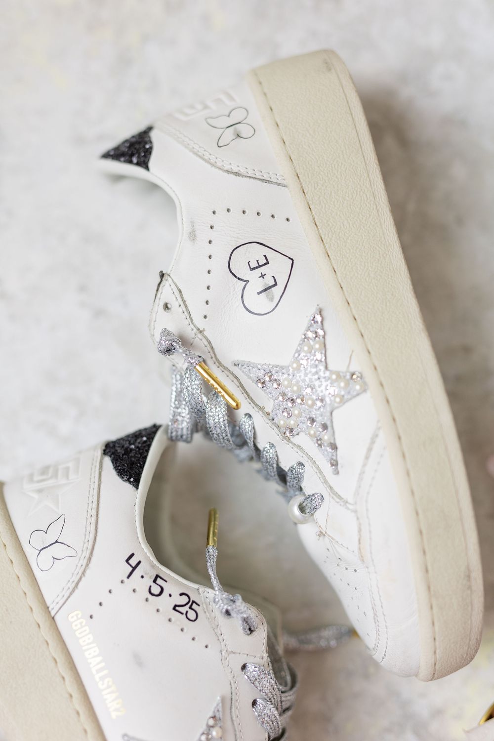Custom white Golden Goose bridal sneakers with glitter star, rhinestone laces, and wedding date 4-5-25 written on sole.