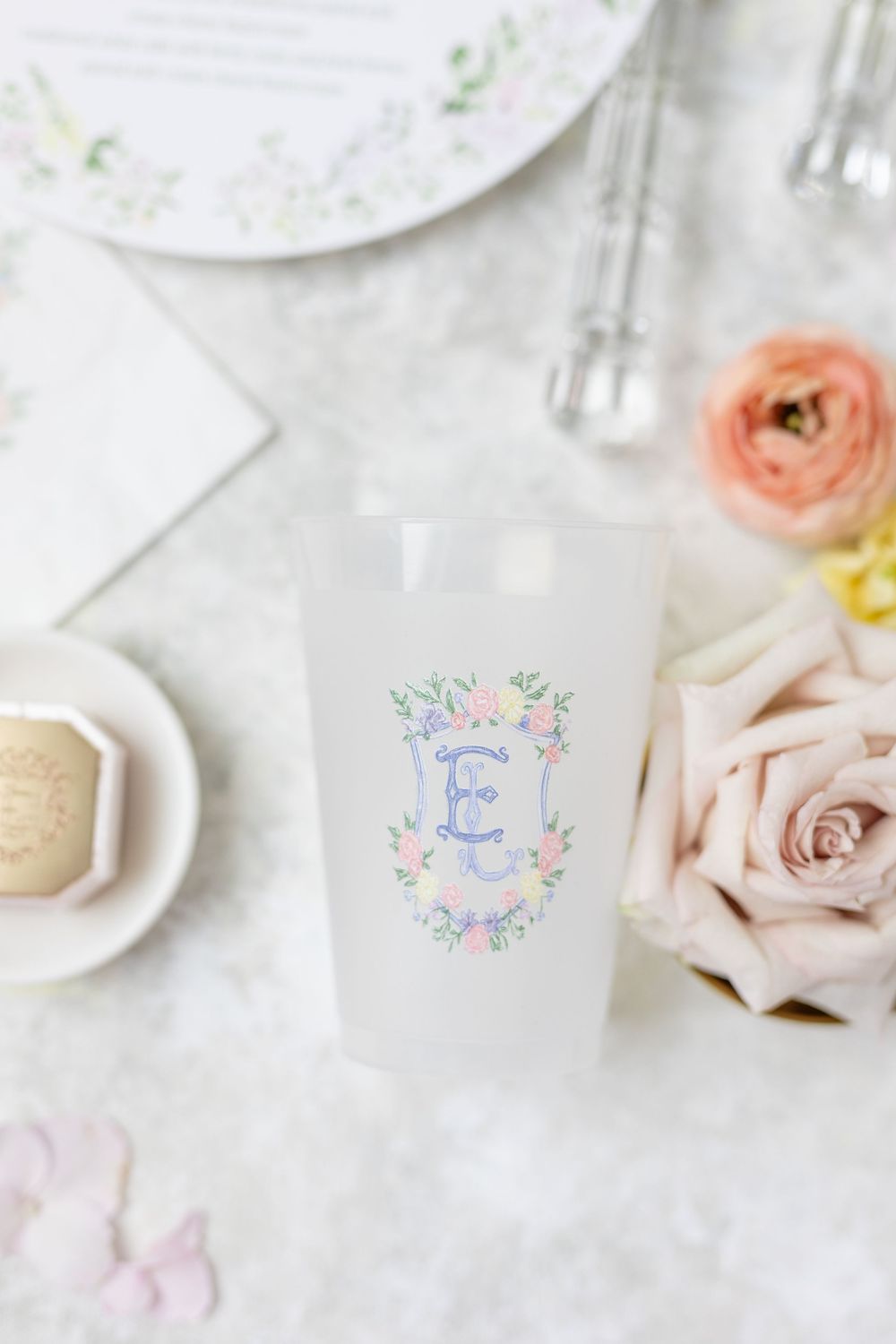 Frosted cup with colorful monogram floral crest design for wedding reception.
