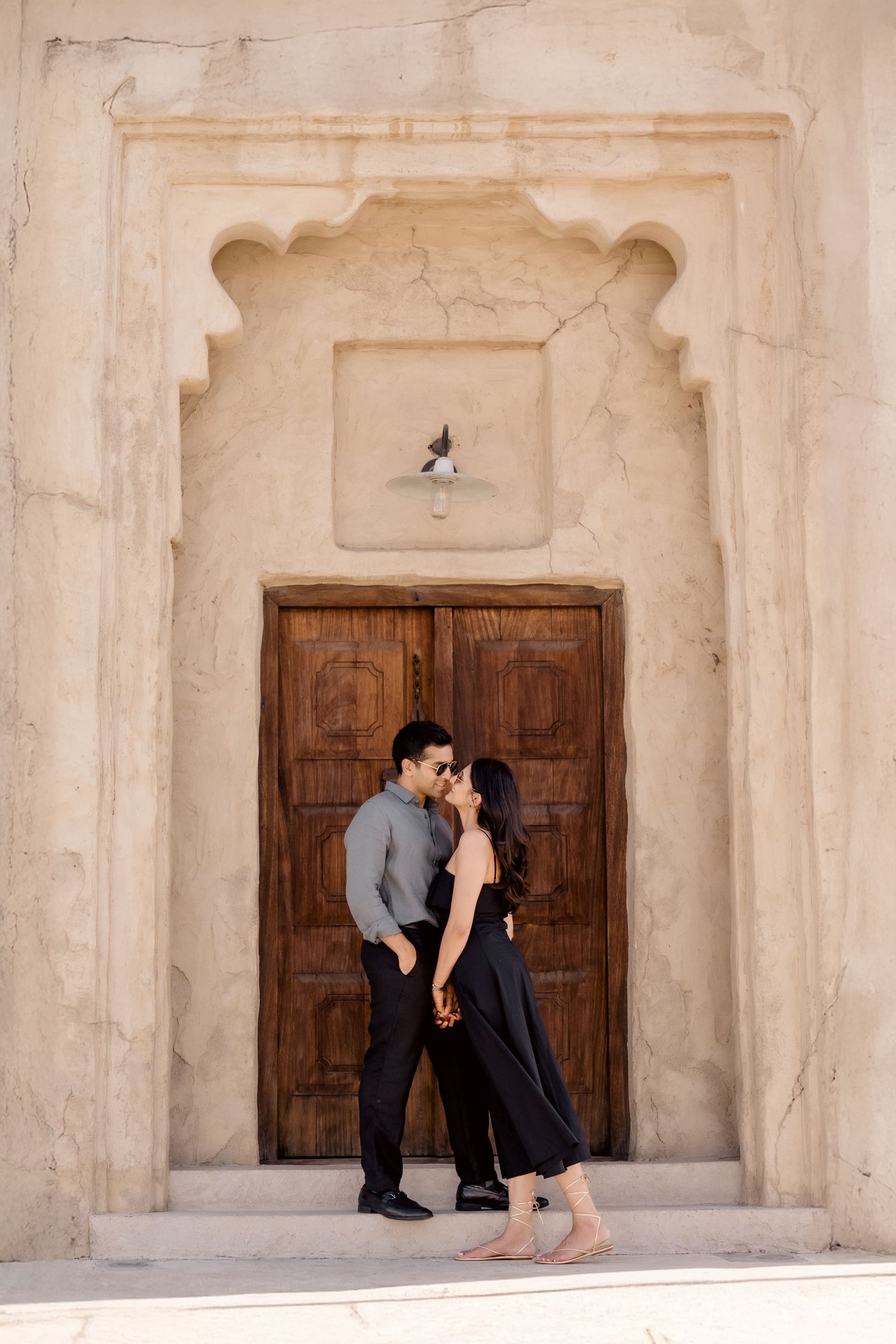 Elegant couple posing in front of carved wooden door during engagement session