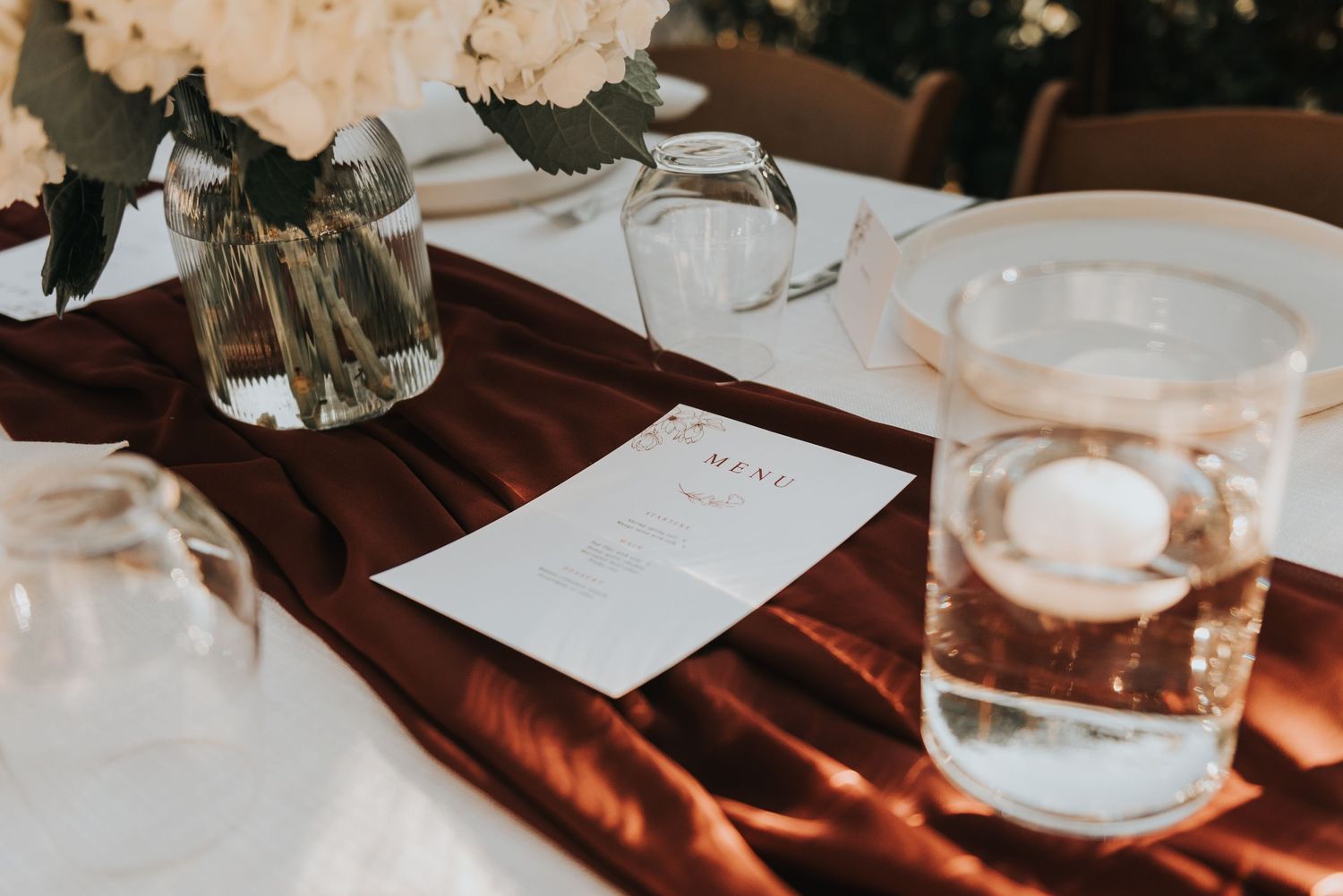 Menu card and glass of water on a rustic wooden table with natural lighting casting warm shadows.