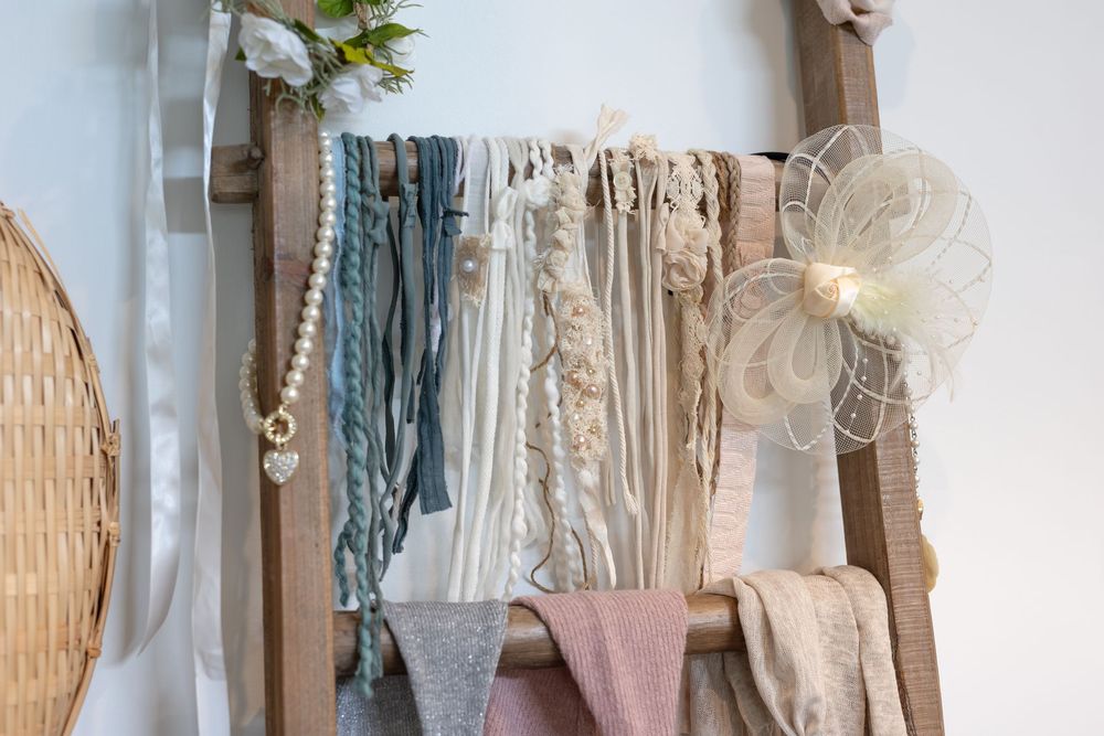 A collection of neutral and pastel colored fabrics and textiles hanging on display with decorative accents.