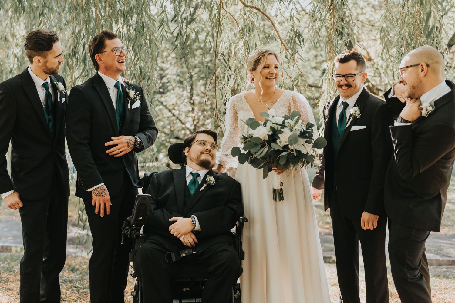 Candid moments captured of wedding party laughing together in a wooded outdoor setting.