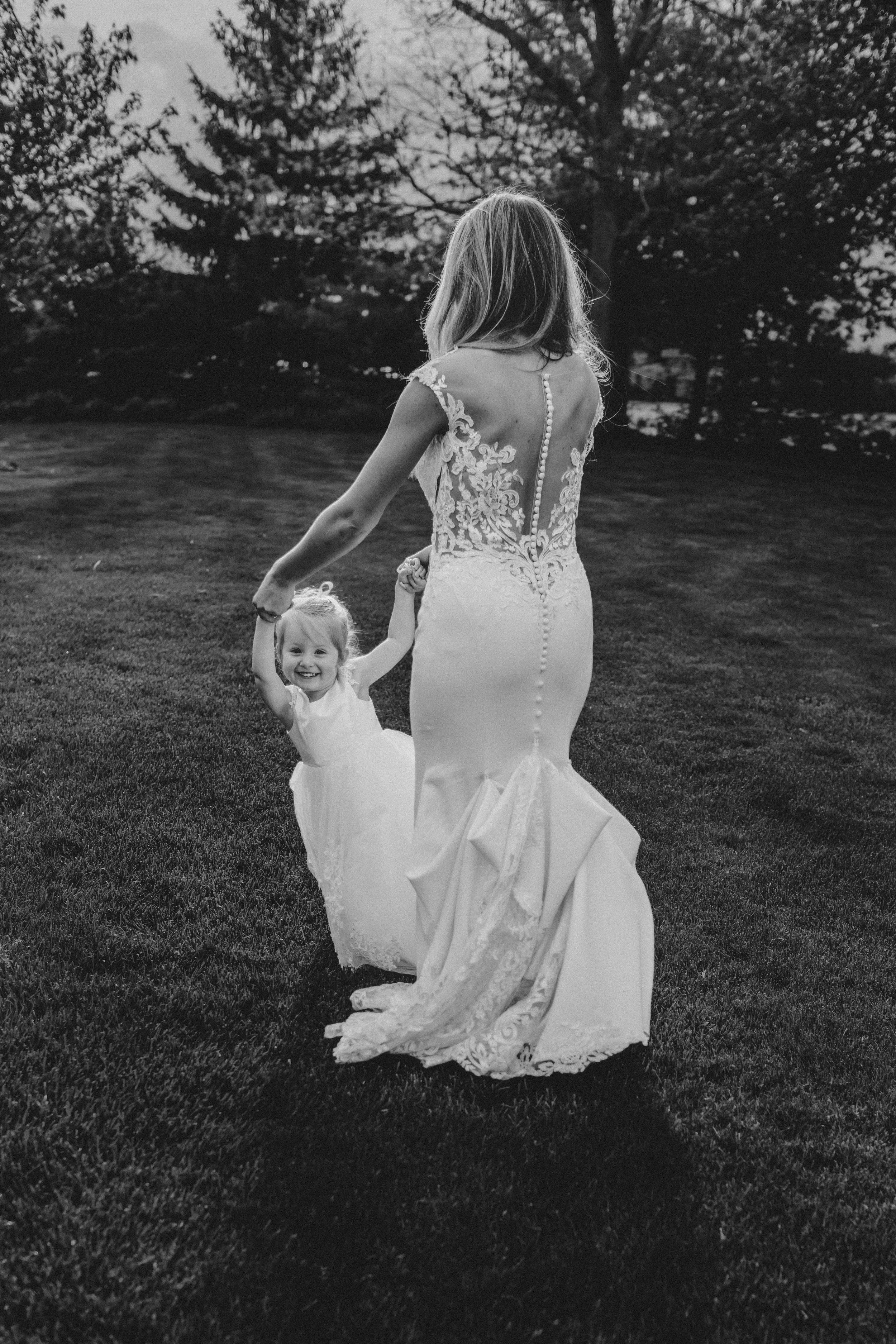 A series of black and white photos showing two figures in white dresses twirling and dancing together on a grassy hill.