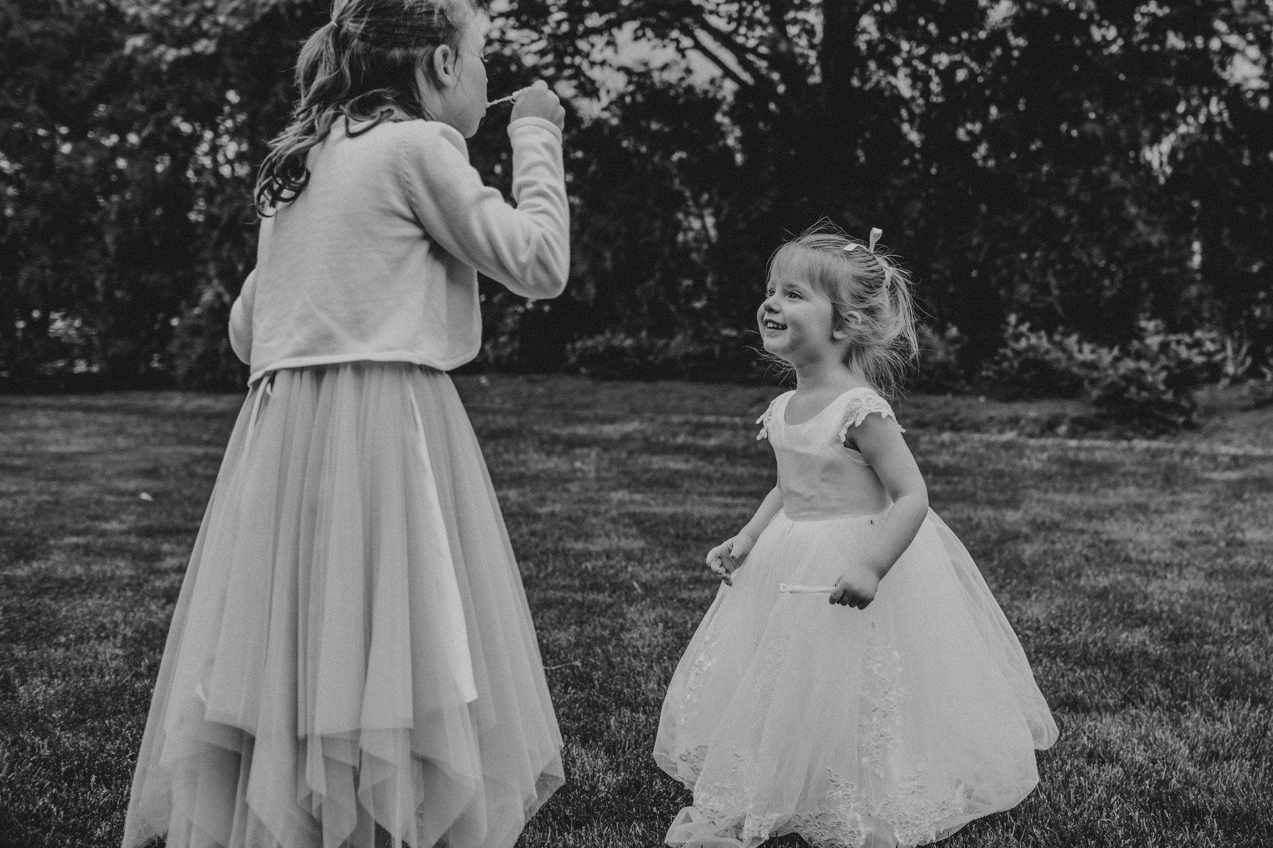 Black and white photo series of children playing and dancing in flowy dresses outdoors in a garden setting.
