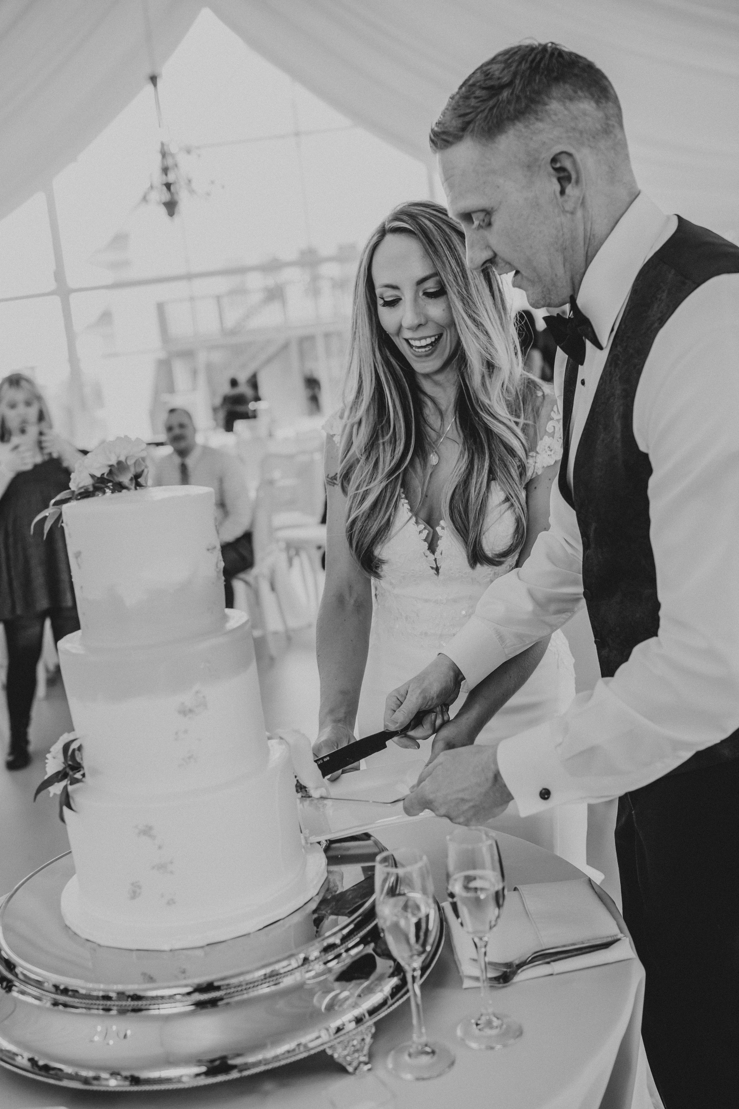 A sequence of three black and white photos showing a couple cutting their wedding cake together at a reception.