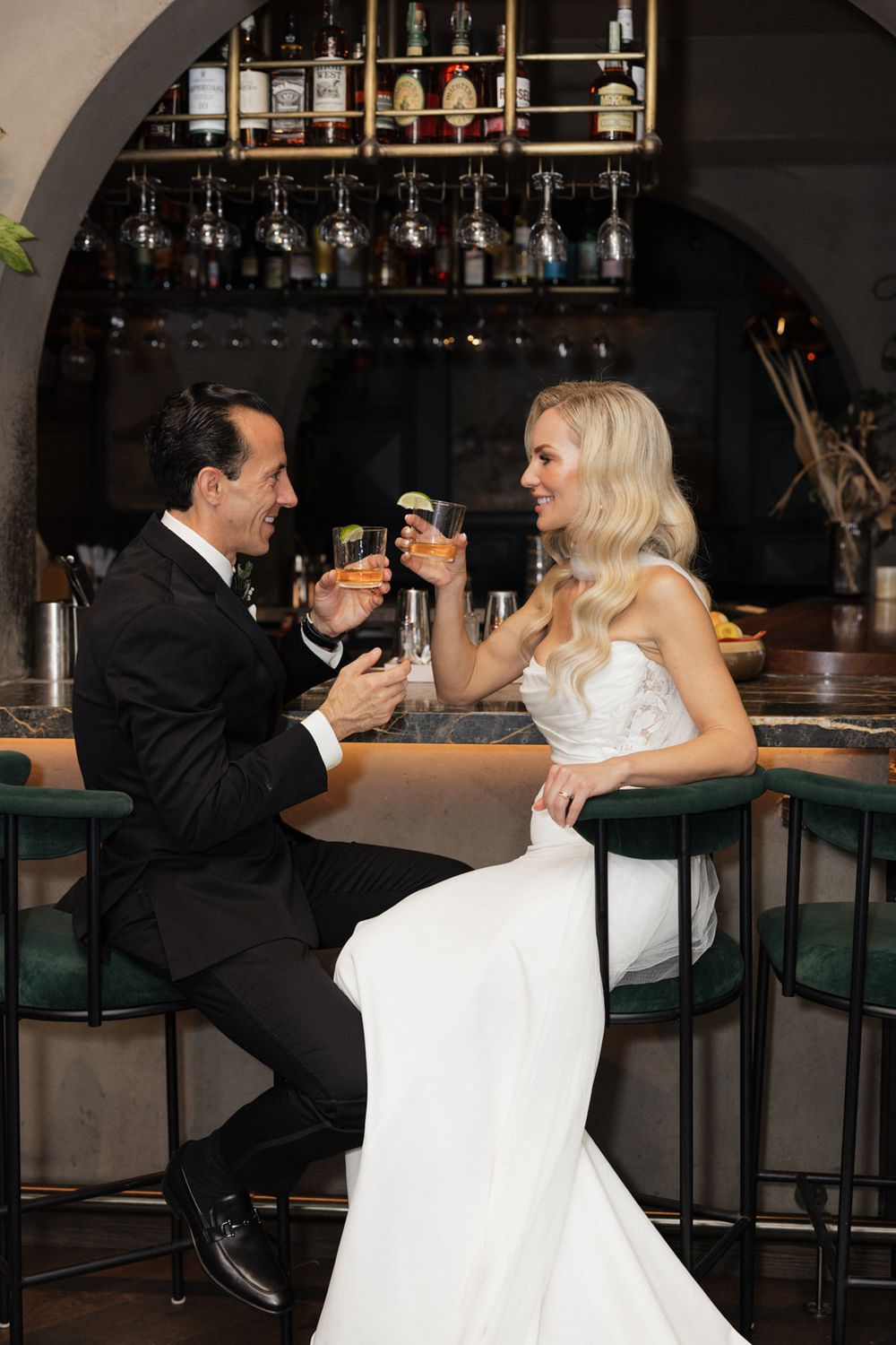 A couple in formal attire shares a romantic moment at an elegant bar counter.